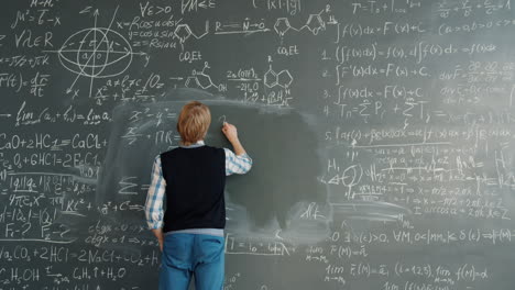student writing equations on a chalkboard