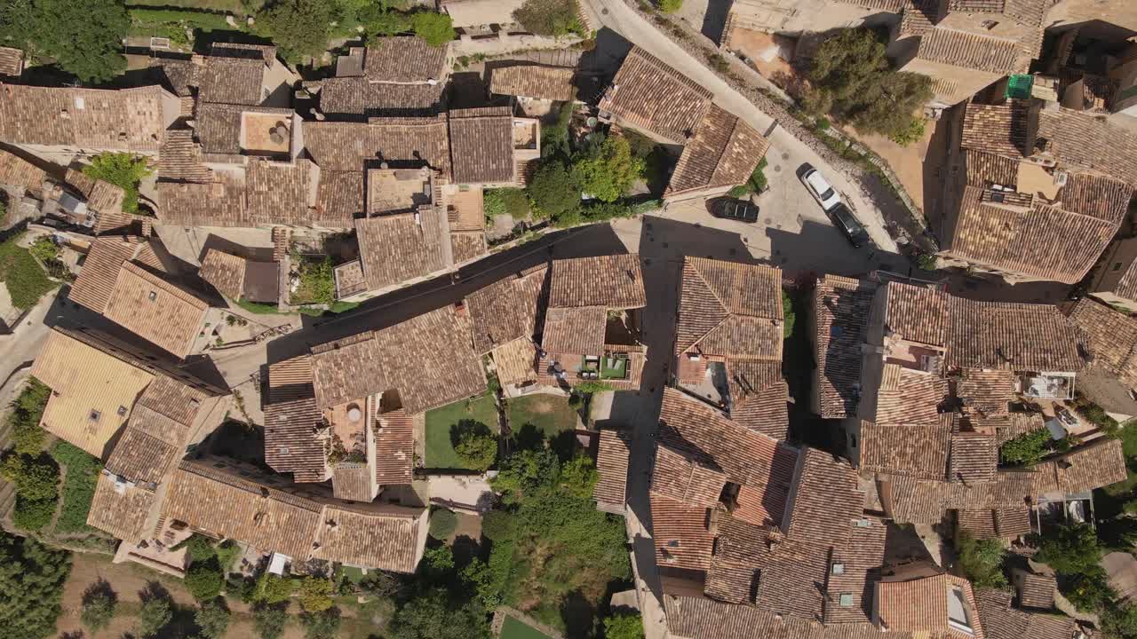 An aerial video showcasing traditional Mediterranean architecture with tightly packed terracotta-roofed buildings and narrow winding streets. The image captures the charm and density of an old village