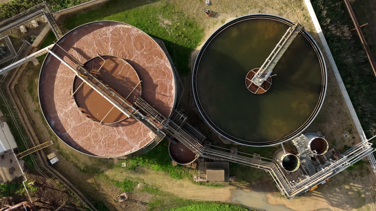 Top down aerial view of industrial pipework and clarifying tanks filled with brown water from sugar production industrial operations. Newark, United Kingdom
