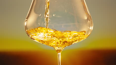 orange or white wine bottle and glass against a sunset in a peaceful vineyard, pouring of ecological natural wine.
