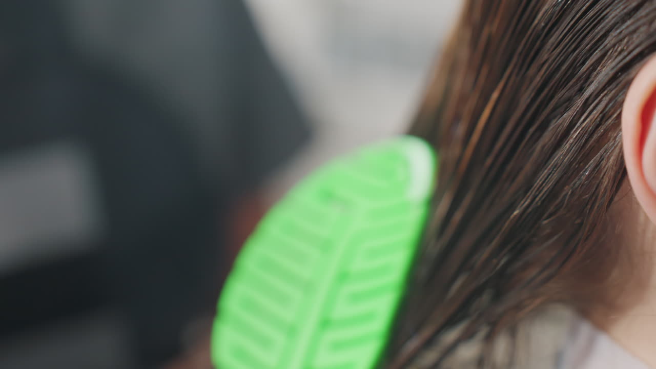 damp hair being carefully groomed professionally, closeup of moist hair meticulously styled in salon setting, detailed shot capturing gentle grooming of shiny wet hair at beauty salon