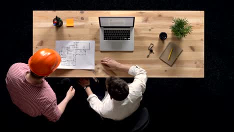 joven está trabajando en la computadora portátil durante el día, el constructor viene y muestra el plan de construcción, concepto de trabajo, concepto de oficina, concepto de comunicación, toma superior