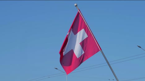 Bandera-Suiza-Flotando-En-El-Viento-Con-Un-Cielo-Azul-Claro-En-El-Fondo