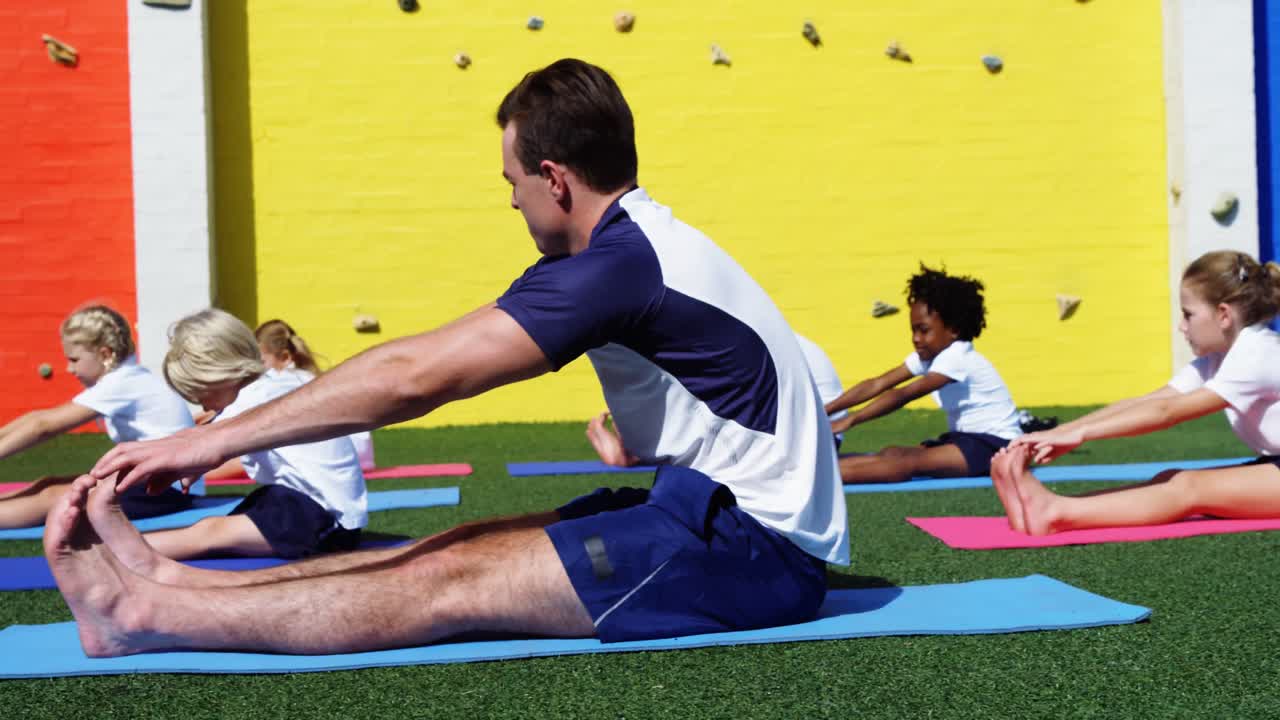 instructor de yoga instruyendo a los niños en la realización de ejercicios