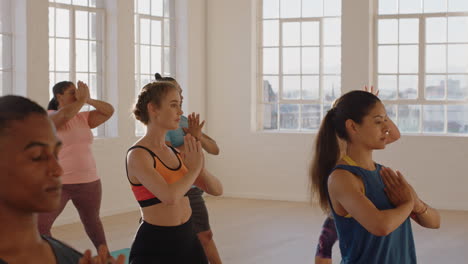 yoga-class-of-young-healthy-people-practicing-prayer-pose-enjoying-exercising-in-fitness-studio-with-instructor-at-sunrise