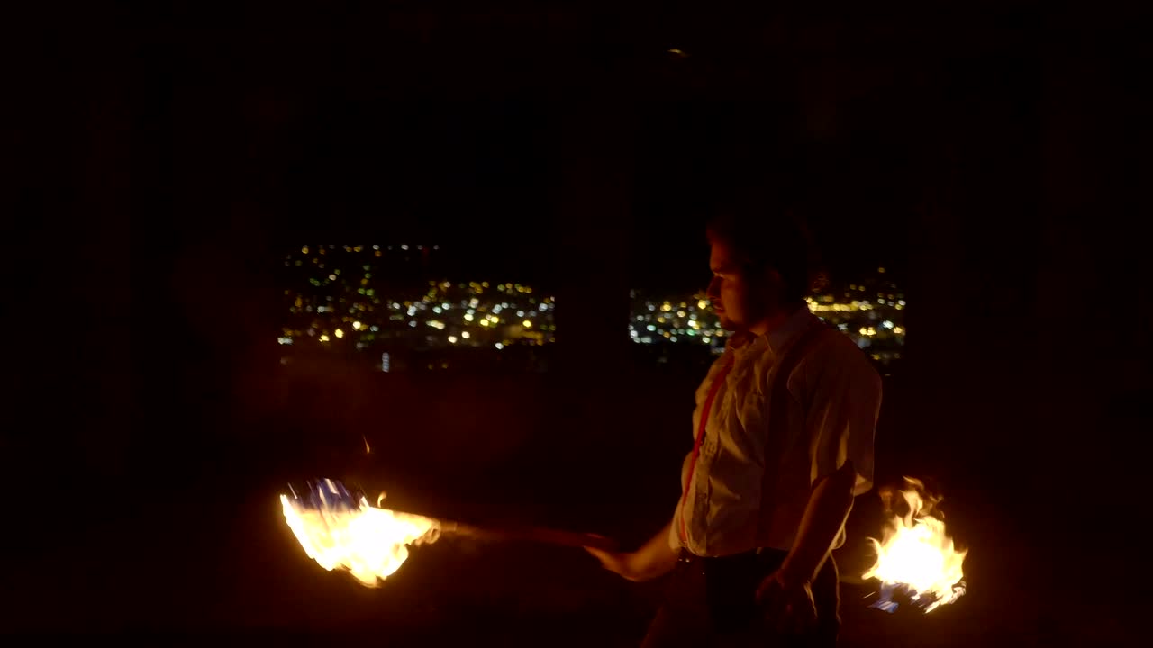 artista masculino realizando un espectáculo de fuego en la oscuridad en cámara lenta.