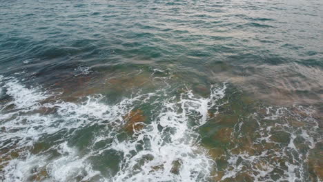 Aerial-top-down-shot-of-waves-reaching-sandy-beach-of-Portugal---Panning-shot