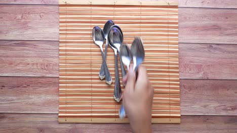 stack of spoons and forks on bamboo placemat