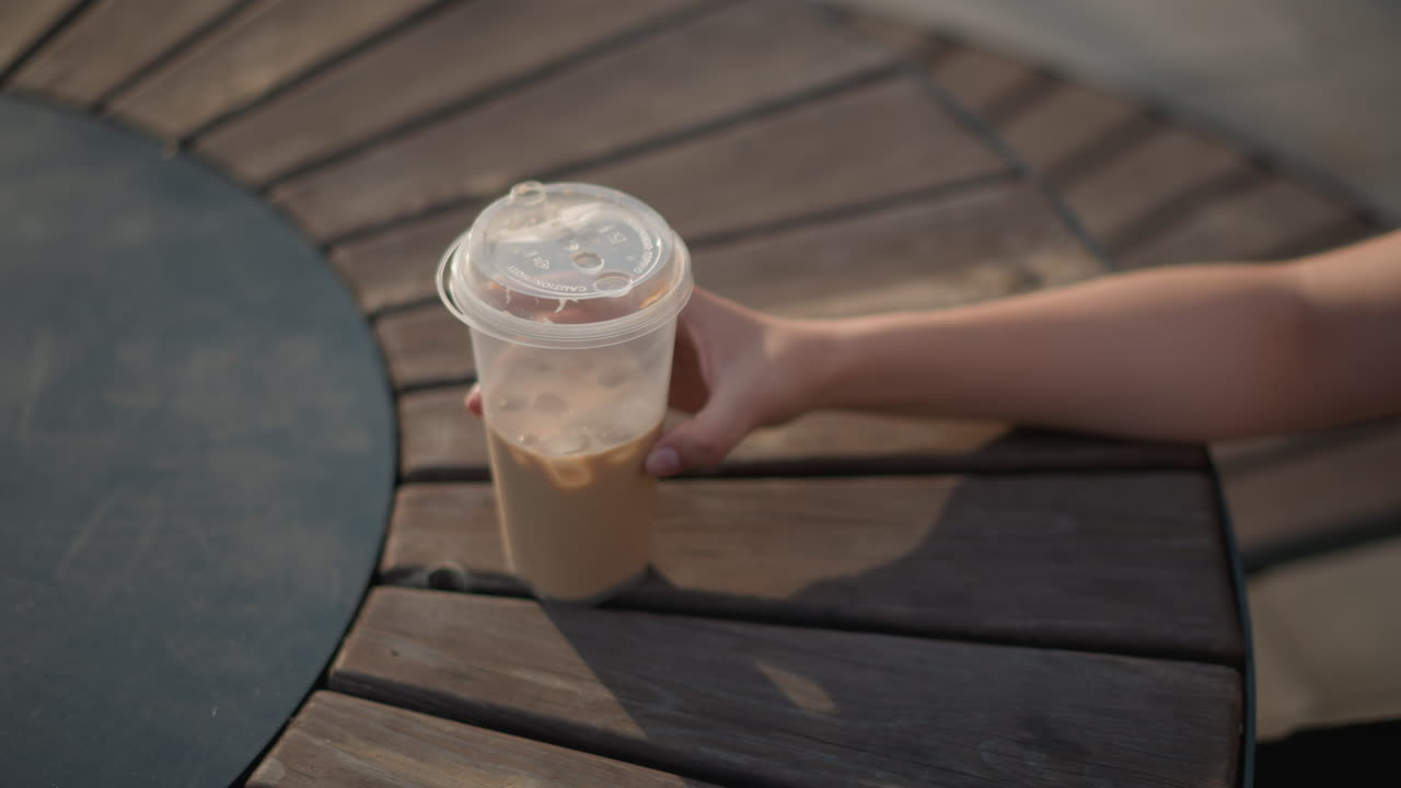 Scena luminosa con caffè, il sole splende sul caffè, la luce solare illumina il tavolo di legno e l'atmosfera della tazza di caffè freddo, accogliente ambientazione nel tardo pomeriggio con caffè freddo su una superficie di legno illuminata dal sole