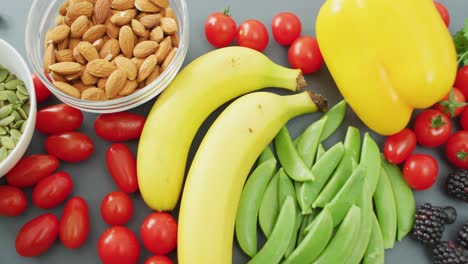 Video-of-fresh-fruit-and-vegetables-and-bowls-of-nuts-and-seeds-over-grey-background