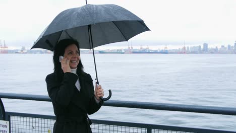 woman holding umbrella and talking on mobile phone