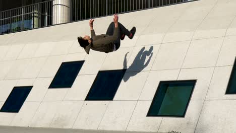 slow motion shot of a young parkour athlete doing a wall backflip in an urban environment