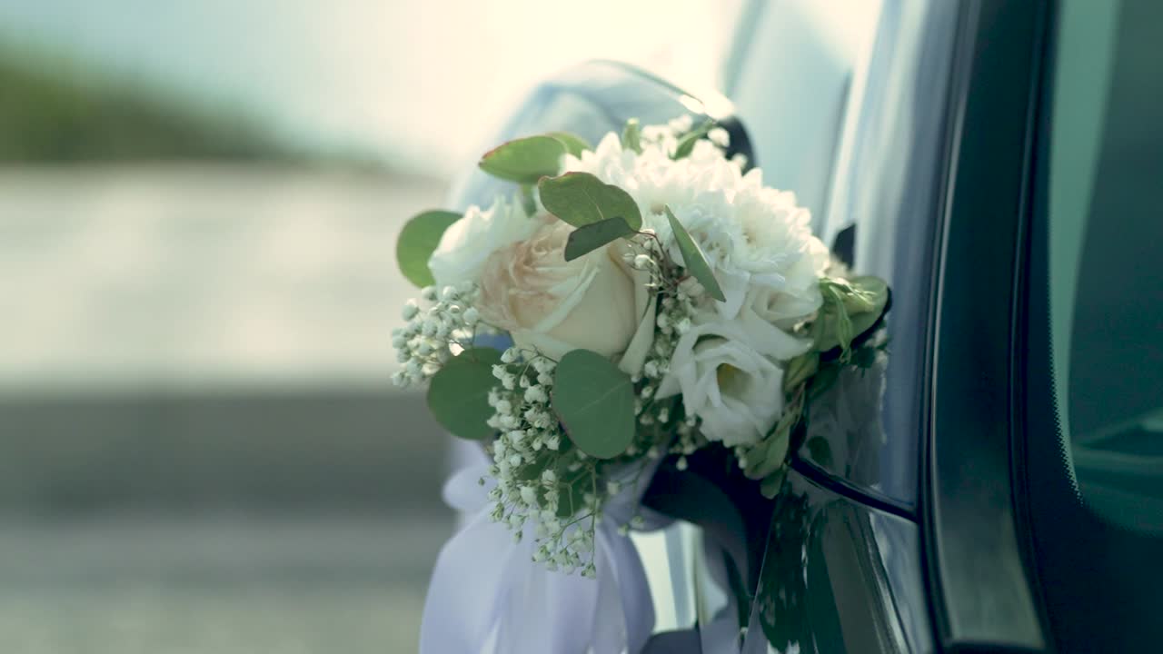 Un'auto è decorata con splendidi fiori nuziali mentre si prepara per la cerimonia. Il sole splende, creando un'atmosfera speciale prima dell'evento.