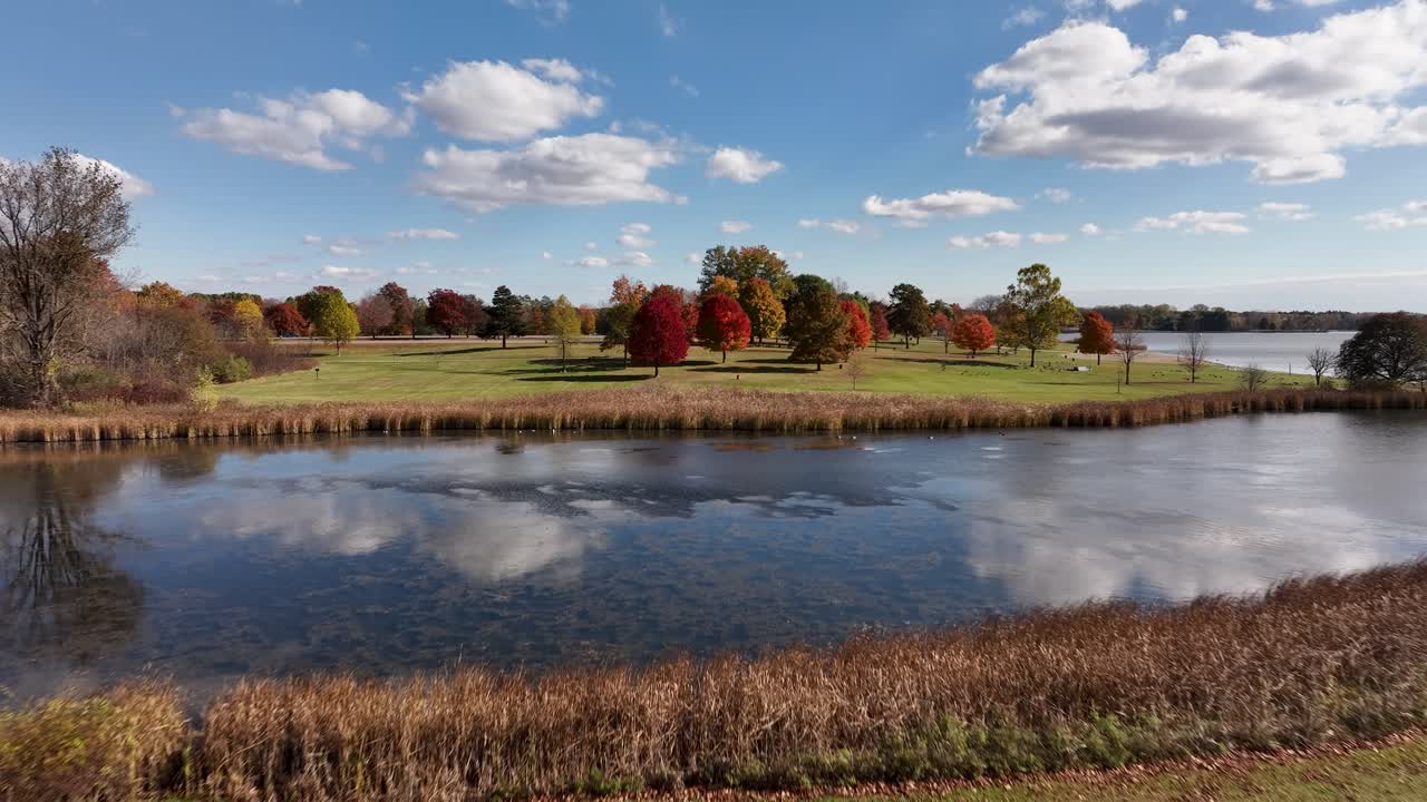 Drone flying toward colorful trees on a beautiful autumn day at Stony Creek Metropark in Shelby Township Michigan