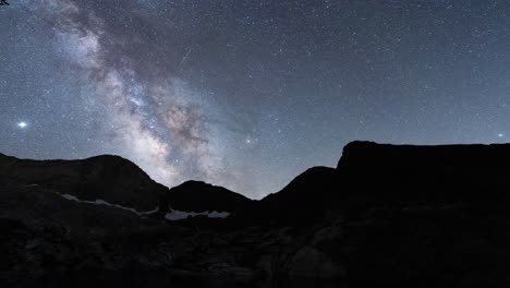 la vía láctea se eleva por encima de las siluetas de las montañas bajo un cielo nocturno claro, toma de time-lapse
