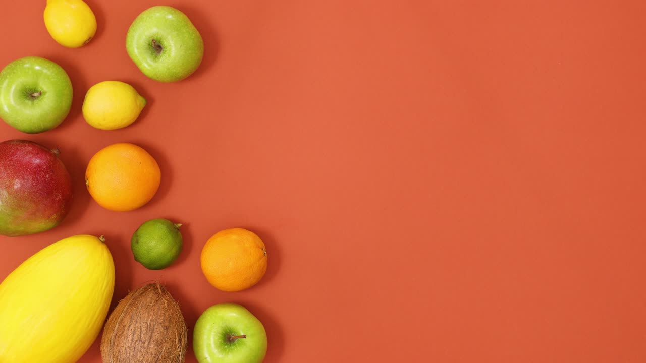 Frutti estivi tropicali che si dispongono sul lato sinistro di uno sfondo arancione. Stop motion