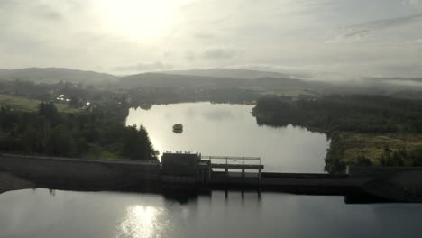 Eine-Luftaufnahme-Des-Lairg-Staudamms-An-Einem-Nebligen,-Sonnigen-Morgen