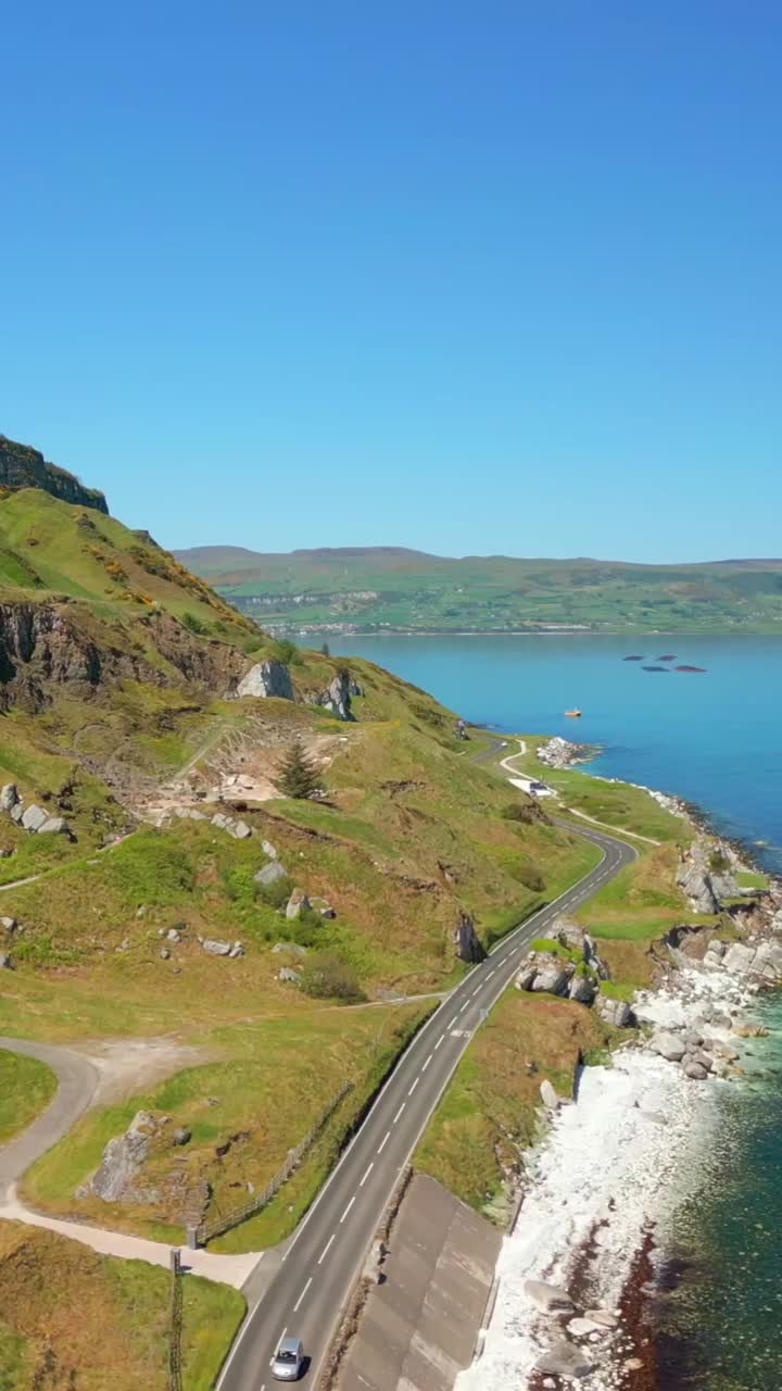 Slow, wide reversing social ratio aerial video of Glenarm on the Causeway Coastal Route on a bright and sunny day. Filmed in 1080x1920 social ratio, in 60fps and with Rec709 color