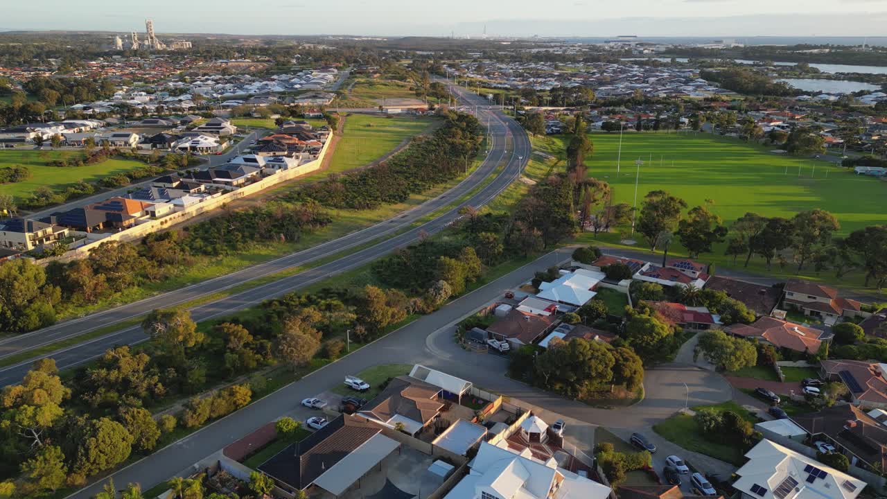 Vista aerea di un'auto che viaggia su un'autostrada curva e deserta in un sobborgo residenziale a Perth, Australia Occidentale
