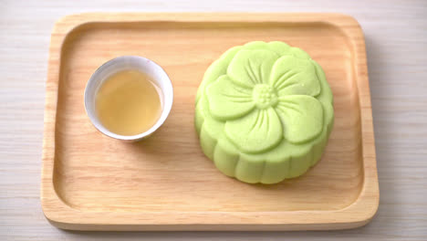 gâteau de lune chinois saveur de thé vert avec thé sur plaque de bois