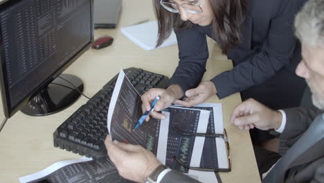 corredor femenino enfocado e inversionista masculino revisando informes en papel