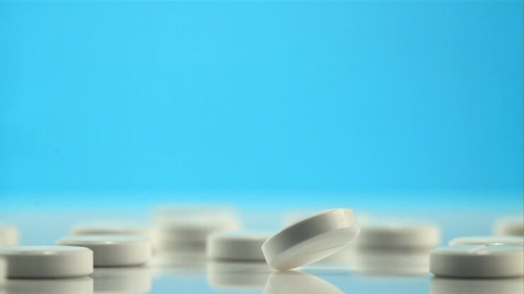 White Pill Falling and Bouncing in Slow Motion on Blue Background