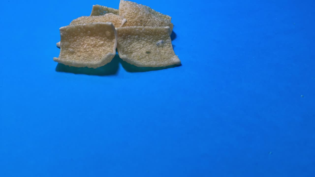 파란색 표면에 굴러가는 토르티야 칩을 닫습니다