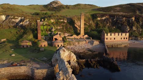 porth wen abandoned coastal derelict brickworks remains golden sunrise countryside bay aerial view slow right orbit