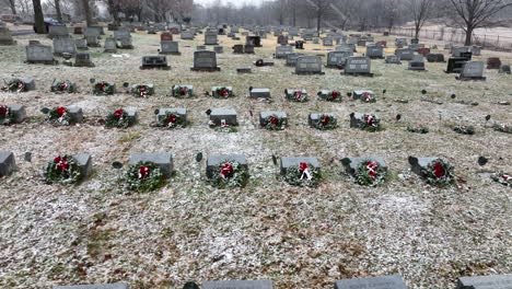 funeral graveyard cemetery headstone markers decorated with christmas wreaths during snow storm