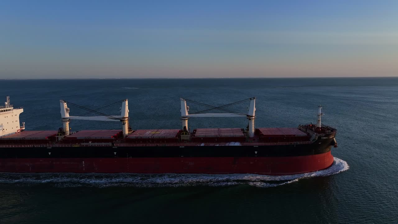 el barco rojo tomini unity navegando por las aguas de holanda hacia la puesta de sol.