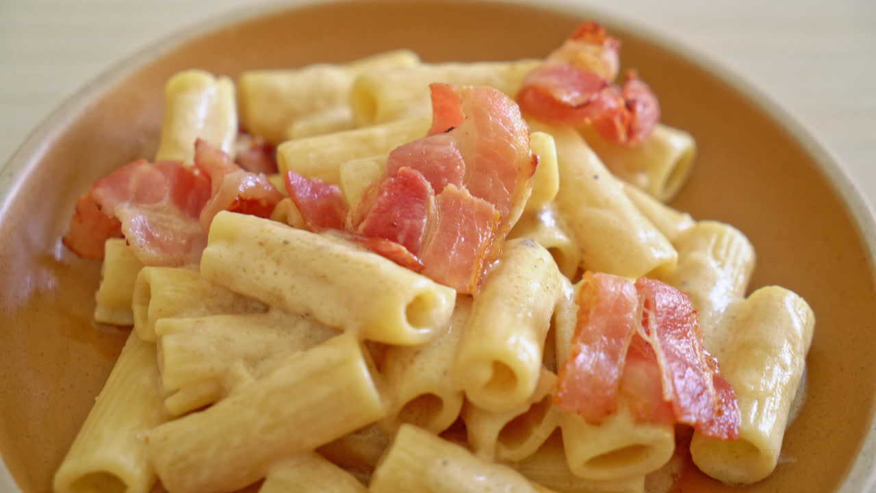 espaguetis rigatoni caseros con salsa blanca y tocino - estilo de comida italiana