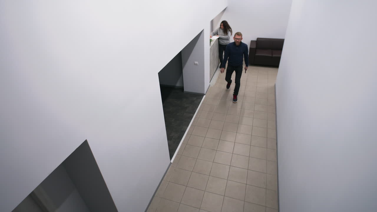 A view of a modern office hallway and reception area, both with and without people