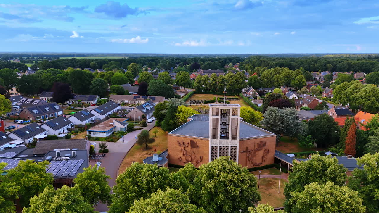 Drone footage approaching the Theobalduskerk in Overloon, Netherlands. Scenery of the green picturesque residential area of the village at daytime