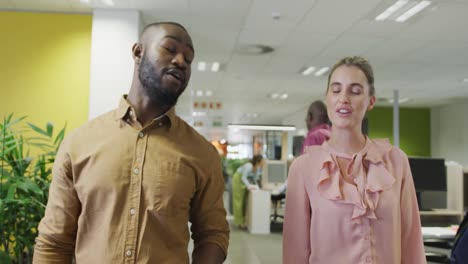 Diverse-male-and-female-business-colleagues-talking-and-walking-in-office