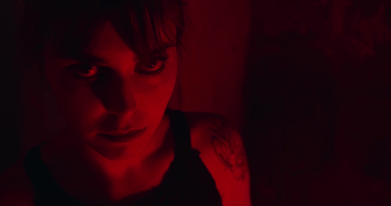 Donna psicopatica con uno sguardo furioso sul viso in una stanza illuminata di rosso scuro. Primo piano.