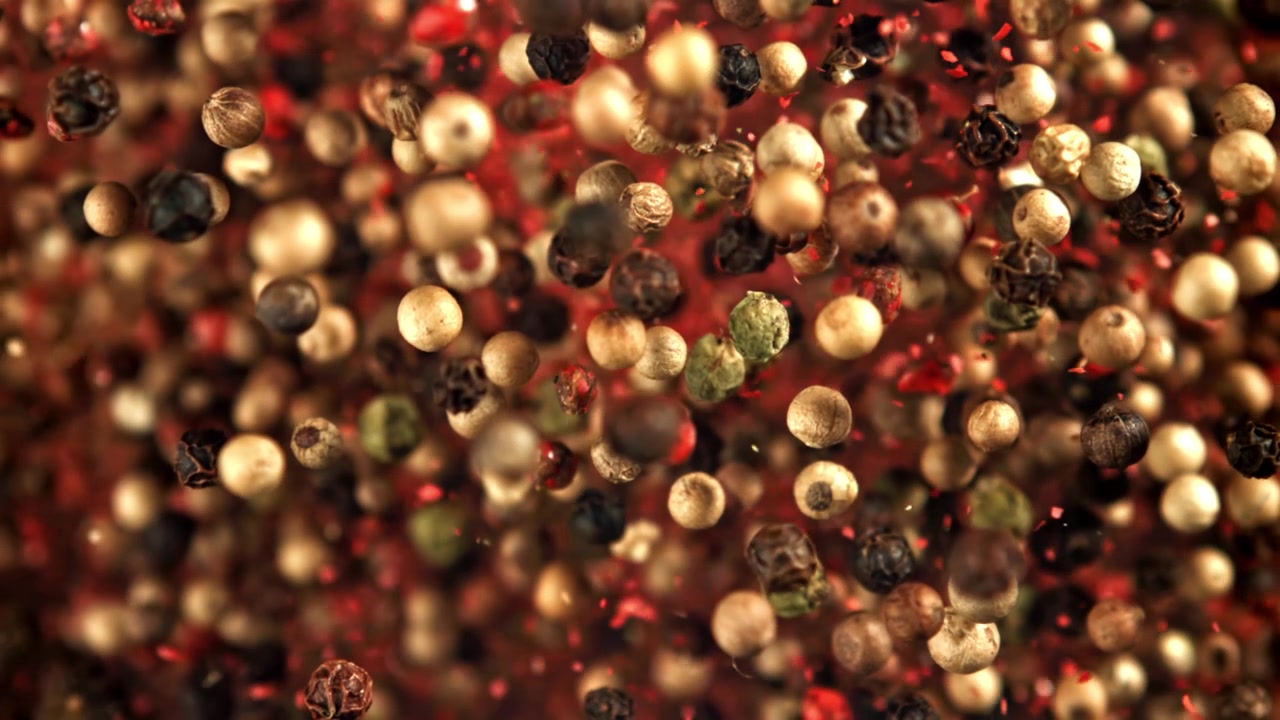 Slow Motion Macro Shot of Mixed Peppercorns and Red Spice