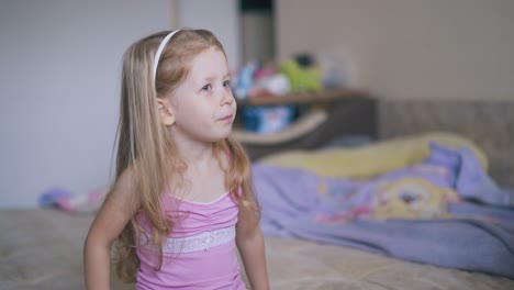 mother gives cough syrup to little girl in pink shirt on bed