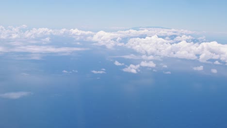 a shot of the beautiful blue sky and puffy white clouds passing by at 10,000 feet