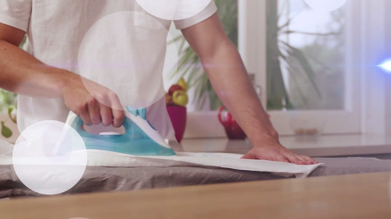 Adult male placing iron onto shirt, gliding iron smoothing wrinkles while light flares