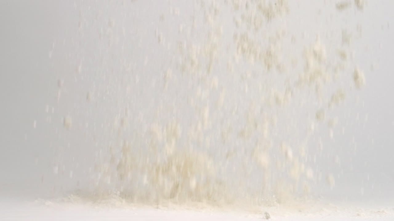 흰 밀가루가 흰색 스튜디오 배경 표면에 떨어지고 4k 느린 동작으로 쌓입니다.