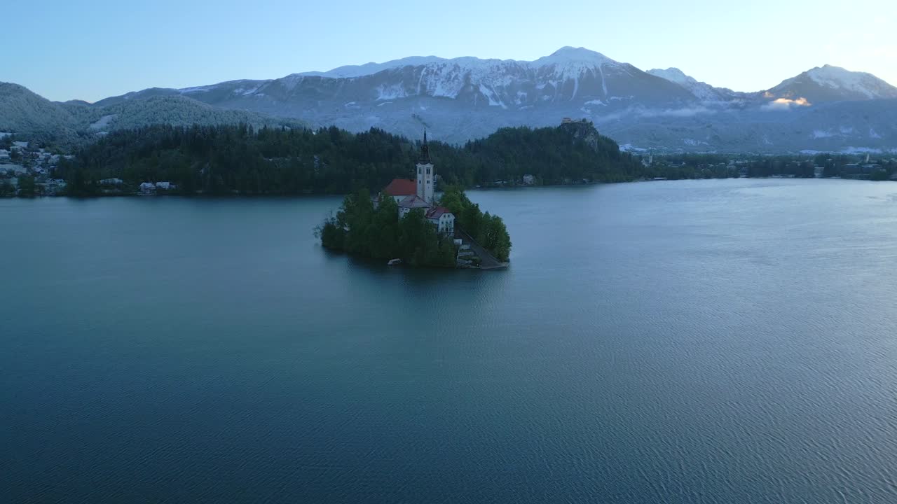Blue hour over the Jamnik Church in the middle of Lake Bled in Slovenia with alpine peaks in the background