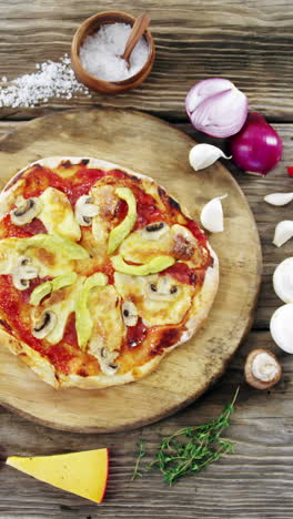 italian pizza on wooden table with vegetables and spices