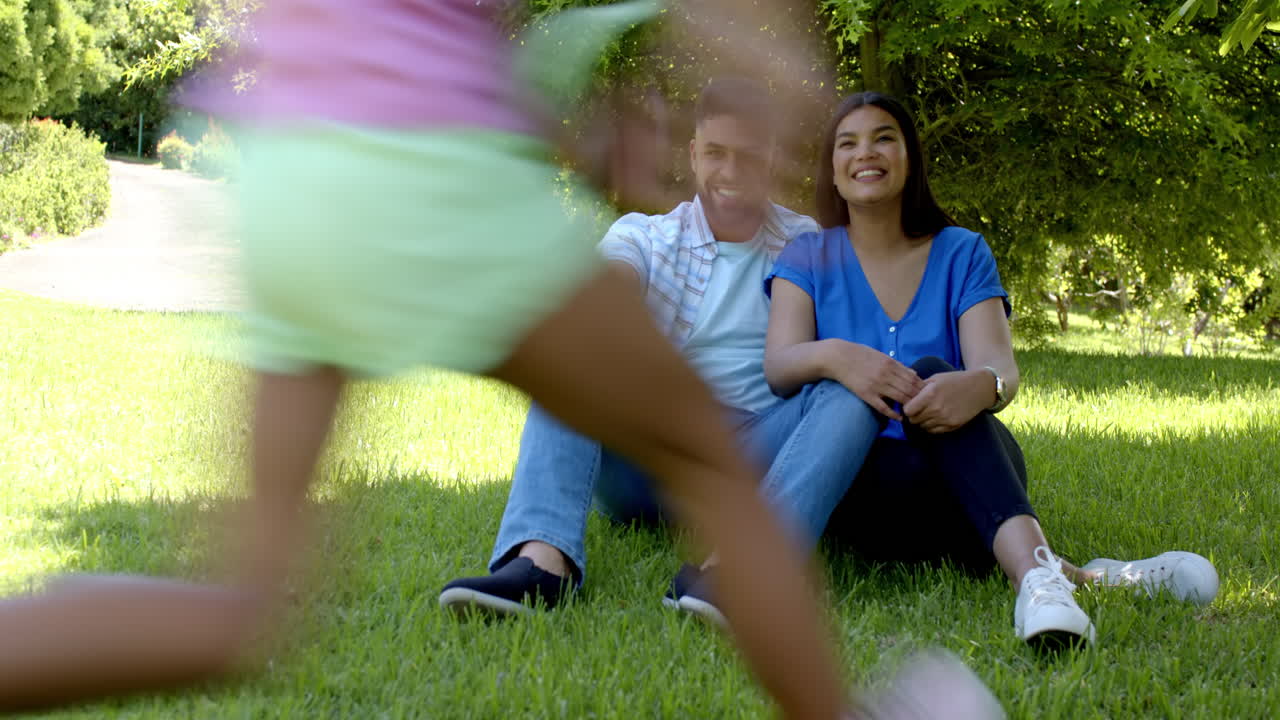 Family playing together in sunny park, sharing joyful moments outdoors