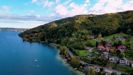 Aerial-view-of-a-vibrant-village-nestled-between-a-sparkling-lake-and-snow-capped-mountains