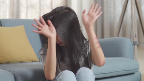 close up of young asian woman victim of violence with bruise on body making defending gesture and fearing while sitting on the floor at home