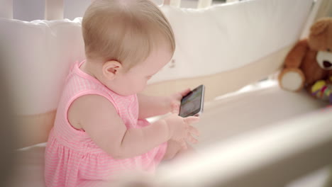 Baby-entertainment-concept.-Cute-baby-with-mobile-watching-animation-in-bed