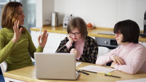 teacher teaches young girls with syndrome using laptop