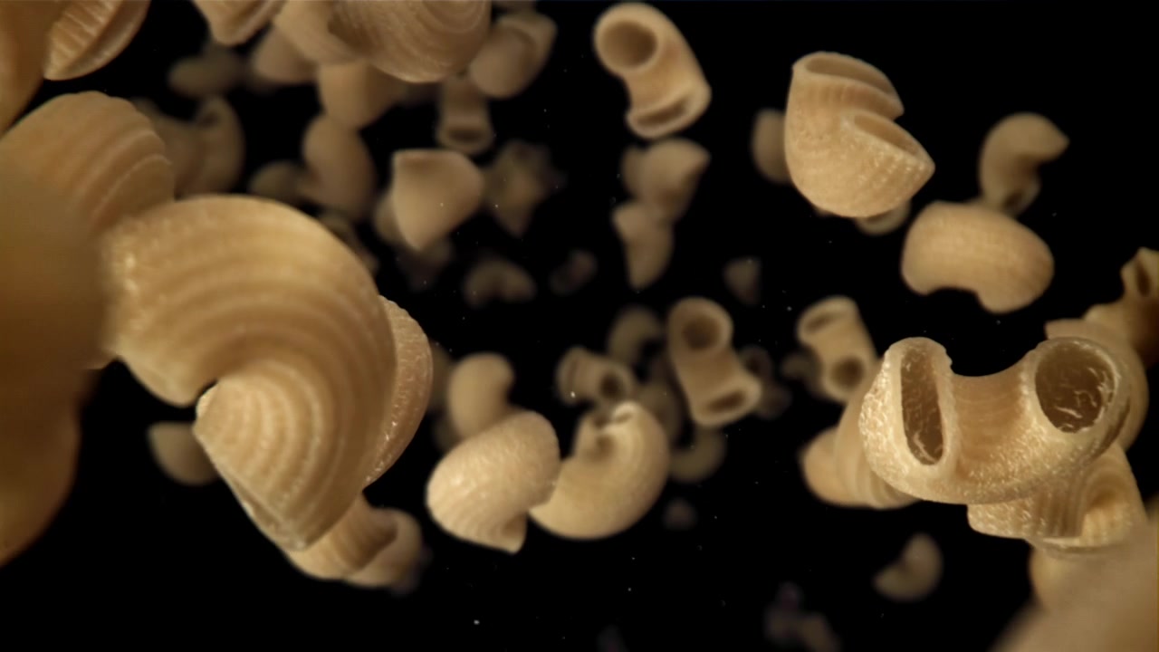 Pasta Maccheroni Cruda che Cade al Rallentatore su Sfondo Nero.