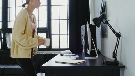 mujer trabajando en la oficina de casa con computadora y café