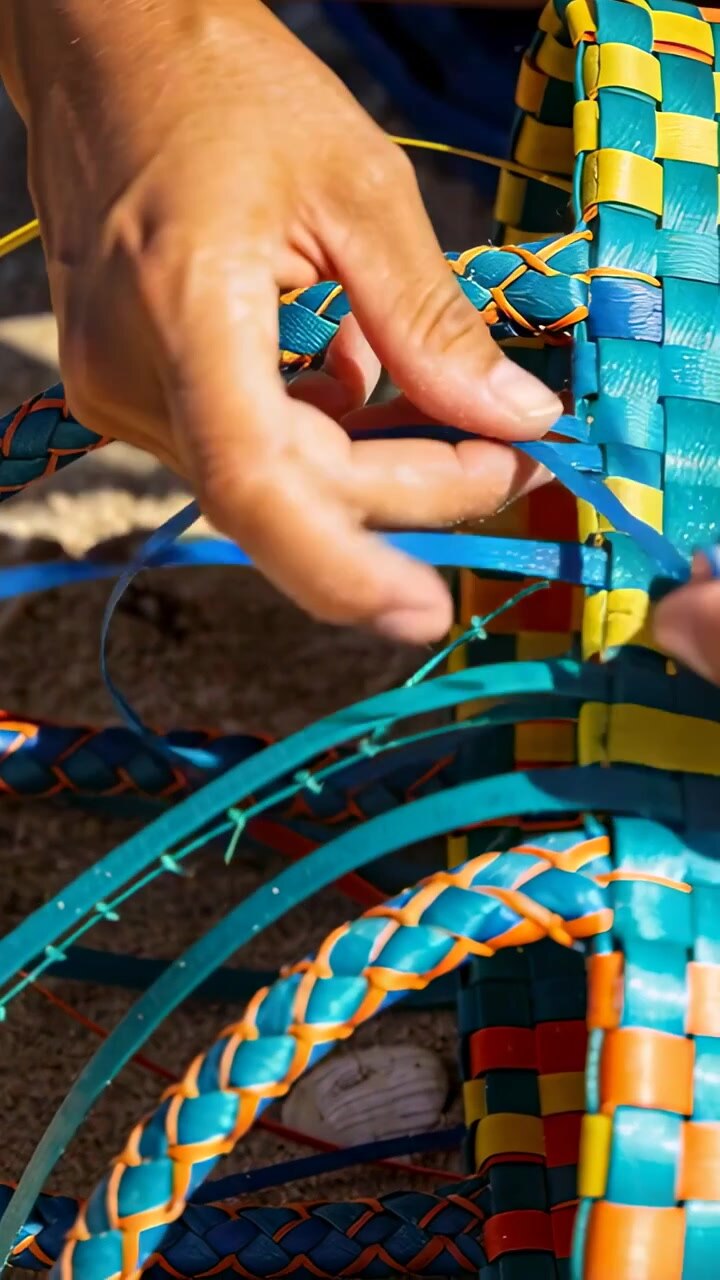 Vertical video: Picking blue strip, hands tucking into woven seat at bench, repairing with cord